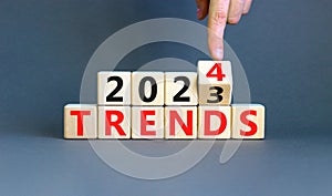 2024 trends new year symbol. Businessman turns a wooden cube and changes words Trends 2023 to Trends 2024. Beautiful grey table photo
