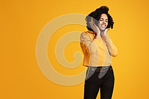 Trendy african american young woman with bright smile dressed in casual clothes and headphones clothing listening music