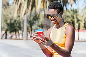 trendy african woman online shopping with credit card and smart phone in the street. photo