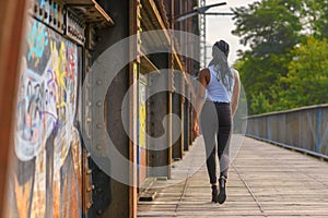 Trendy African woman walking away across a bridge