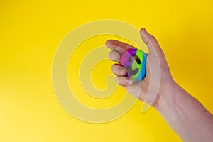 Trendy anti-stress toy snappers in mans hand on yellow background with copy space