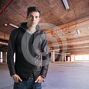 Trendy attractive young man standing in empty warehouse