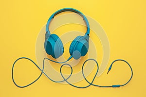 Trendy blue headphone on yellow background. Music concept.