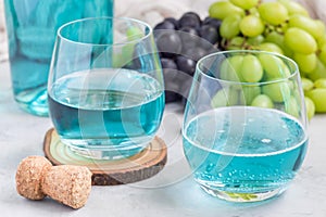 Trendy blue moscato wine in glass and in bottle, green and red grape on background, horizontal