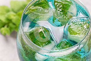 Trendy blue moscato wine in glass, served with mint ice cubes, horizontal, closeup