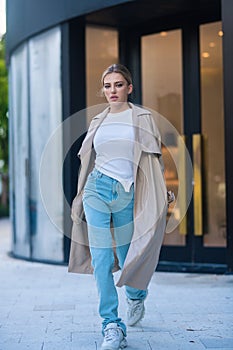 Trendy coat. High fashion model walking on city street. Girl fashion style. Fashion beautiful elegant woman. Young woman