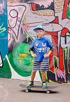 Trendy confident little boy posing on a skateboard