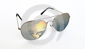 Trendy cool silver sunglasses with the reflection of a beautiful sunset over an ocean