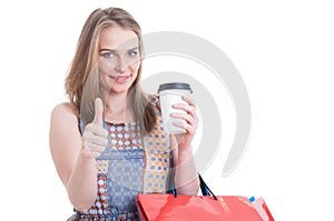 Trendy cute female holding coffee mug and carrying shopping bags