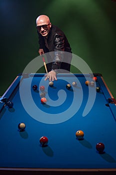 Trendy dude playing a game of pool in a nightclub