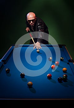 Trendy dude playing a game of pool in a nightclub