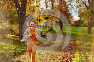 trendy female in fitness clothes in park running