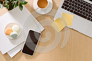Trendy feminine home office workspace. White office desk. Laptop, coffee cup and macaroons, phone, notebook, pencil. Flat lay, top
