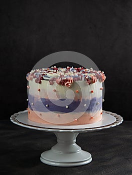 Trendy festive colorful cake on cake stand over dark background with free space for text ,vertical.