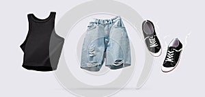 Trendy flying cotton tank top, blue jeans shorts and sneakers isolated on gray background. Clean black crop top. Branding clothes