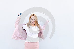 Trendy girl in a white T-shirt and a pink fur coat with a smartphone in her hands and headphones