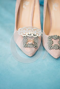 Trendy, graceful suede high heel shoes and wedding rings and jewelery in a blue suede chair. Wedding details.