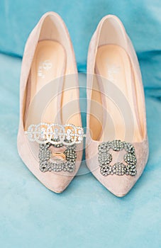 Trendy, graceful suede high heel shoes and wedding rings and jewelery in a blue suede chair. Wedding details.