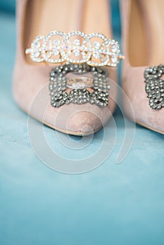 Trendy, graceful suede high heel shoes and wedding rings and jewelery in a blue suede chair. Wedding details.