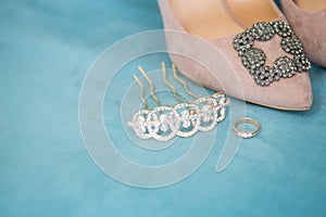 Trendy, graceful suede high heel shoes and wedding rings and jewelery in a blue suede chair. Wedding details.