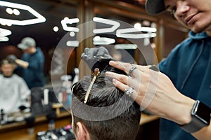 Trendy haircut. Close up shot of professional male barber working with scissors and hair comb, making haircut for client