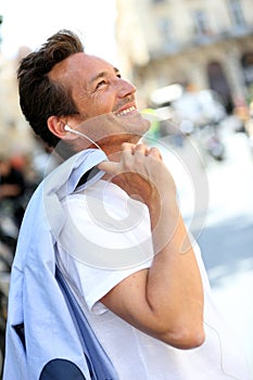 Trendy handsome man smiling listening to music in town