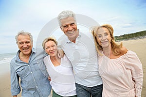 Trendy happy senior people walking on the beach