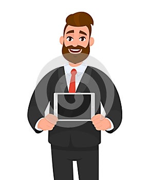 Trendy happy young bearded business man showing/holding blank screen of digital tablet computer in hands. Modern technology.