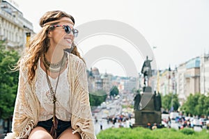 Trendy hippie woman tourist relaxing on stone parapet in Prague