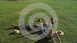 Trendy Hipster Girls Relaxing on the Grass . Summer lifestyle portrait of three hipster women laying on the grass enjoy