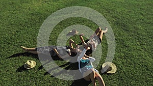 Trendy Hipster Girls Relaxing on the Grass . Summer lifestyle portrait of three hipster women laying on the grass enjoy