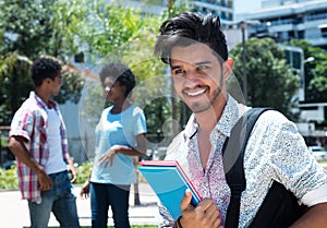 Trendy latin male student outdoor on campus with friends