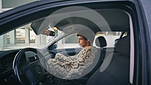 Trendy man get car passenger seat in residential area. Hipster fastening belt
