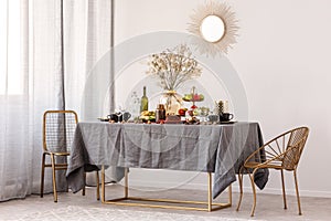 Trendy mirror in golden frame on white wall of elegant dining room