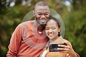 Trendy, modern couple taking selfie on phone while on a romantic date in a park and sharing relationship status on