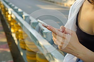 Trendy modern millennial fashion woman sitting in the park uses smartphone application to stay connected on social media.