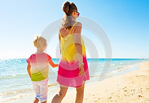 Trendy mother and child on seacoast walking