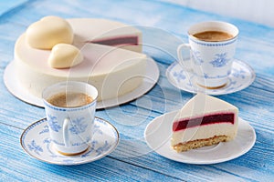 Trendy mousse cake. Slice of cake on a plate. Cup of coffee. Wooden background.