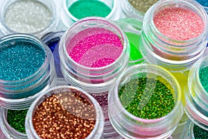 Trendy multicolored glitter in jars. Shimmer, sparkle for makeup, manicure. Shiny powder, pigments. Cosmetic products.