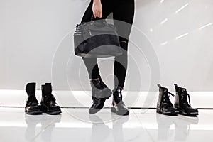 Trendy new collection of seasonal women`s shoes and bags. Close-up of female legs in stylish black jeans in boots with a leather