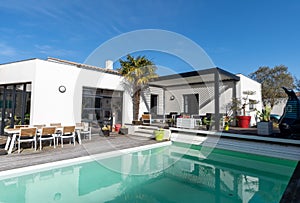 Trendy outdoor patio pergola. garden lounge, chairs, metal grill surrounded by landscaping