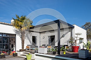 Trendy outdoor patio pergola. garden lounge, chairs, metal grill surrounded by landscaping photo