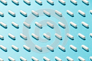 Trendy pattern made with Pharmaceutical medicine pills, tablets and capsules on bright light blue background