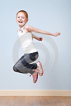 Trendy red-haired girl jumping indoors