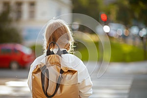 Trendy school girl crossing crosswalk and going to school