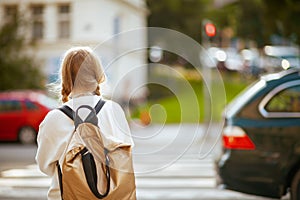 Trendy school girl crossing crosswalk and going to school