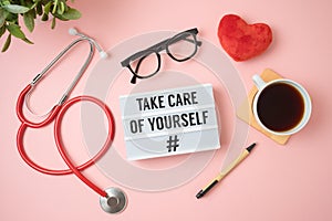 Trendy self care concept with light box, heart shape and stethoscope on pink background photo