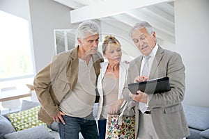 Trendy senior couple with real-estate agent visiting new house
