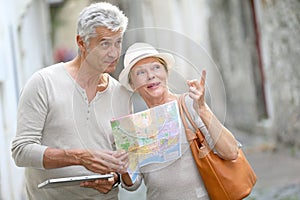 Trendy senior tourists visiting town using tablet and map photo