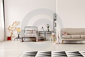 Trendy sofa in scandinavian design kid`s bedroom with industrial furniture and patterned black and white rug on the floor